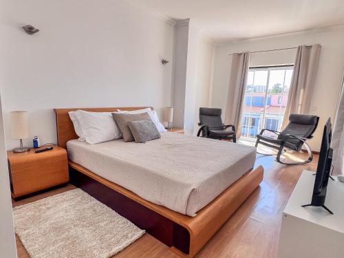 a bedroom with a bed with two chairs and a television at Silver Globe in Albufeira