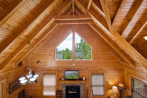 a room with a fireplace in a log cabin with a window at Mountain Sunrise by Avada Properties in Sevierville
