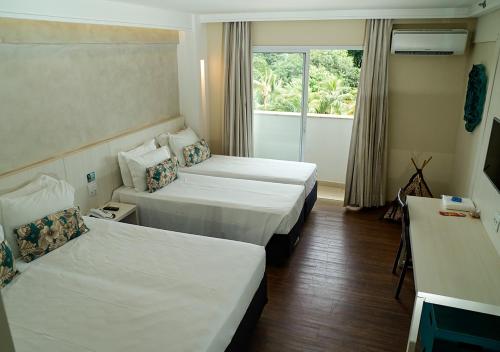 a hotel room with two beds and a window at Hot Beach Celebration in Olímpia