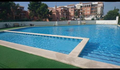a large blue swimming pool with buildings in the background at Apartamento Parque del Duque in Orihuela Costa