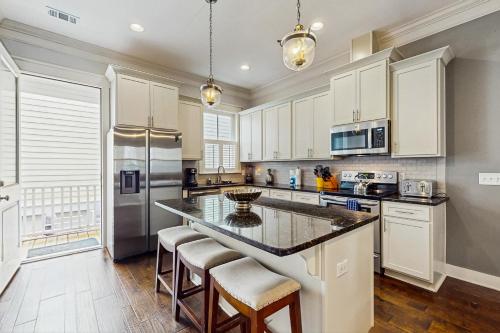 a kitchen with white cabinets and a large island with bar stools at Price Street Place in Savannah