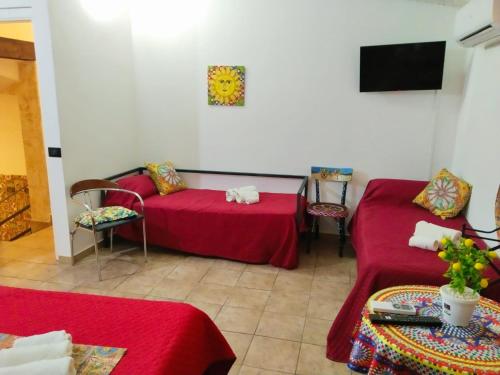 a room with two red beds and a tv at B&B Sikelia in Terrasini