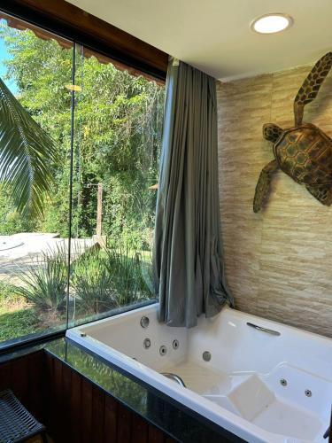 a bath tub with a turtle on the wall next to a window at Cantinho do marinheiro in Paraty