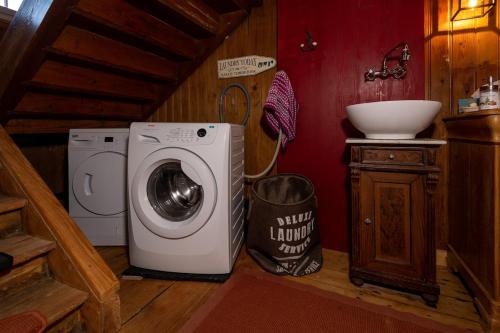 a bathroom with a washing machine and a sink at Ferienhaus Lindeli, Luxeriös eifach in Sankt Peterzell