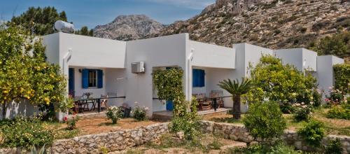 a white house with a mountain in the background at Pleiades Apartments in Lefkos Karpathou