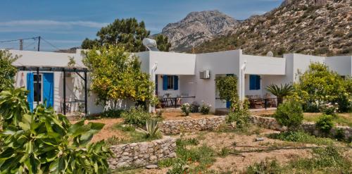 a white house with mountains in the background at Pleiades Apartments in Lefkos Karpathou