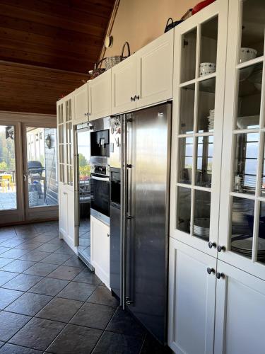 a kitchen with white cabinets and a stainless steel refrigerator at 5 bedroom Spectacular view & charming house in Vollen centre in Vollen