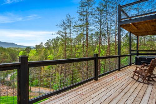 a wooden deck with a chair and a grill on it at Mountain Bliss by Avada Properties in Sevierville