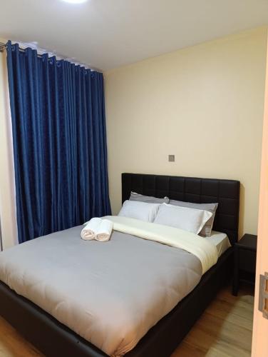a bedroom with a large bed with blue curtains at Pleasant view in Tatu City