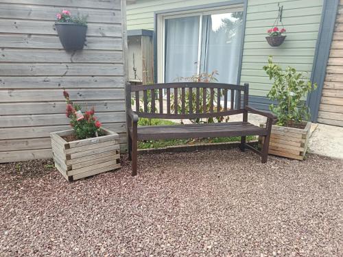 a wooden bench sitting outside of a house with potted plants at Les épines in Quend-Plage