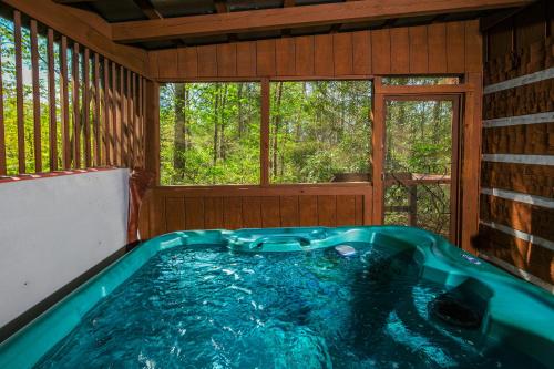 a jacuzzi tub in a cabin with a window at Cozy, secluded 2BR cabin with hot tub & pool table only 1 mile from PF parkway! in Pigeon Forge