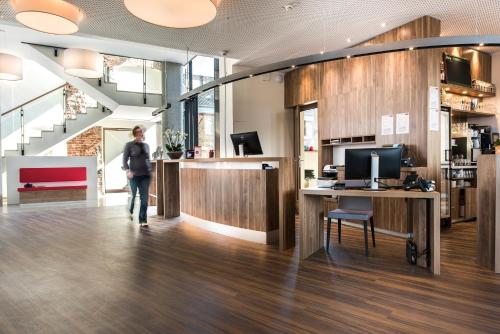 a person walking through an office with a desk and a computer at Alexianer Hotel am Wasserturm in Münster