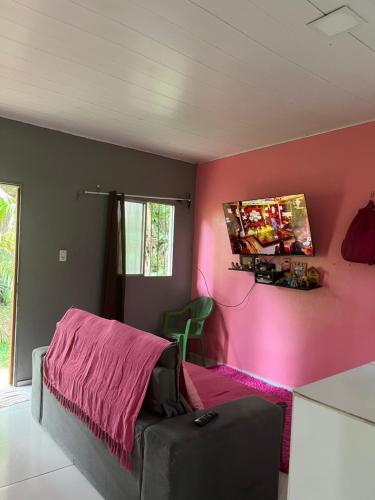 ein Schlafzimmer mit einer rosa Wand mit einem Bett und einem Tisch in der Unterkunft Casa na ilha do combu in Acará