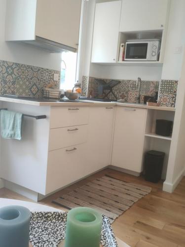une cuisine avec des armoires blanches et un micro-ondes dans l'établissement Charmant studio au calme, à Paris