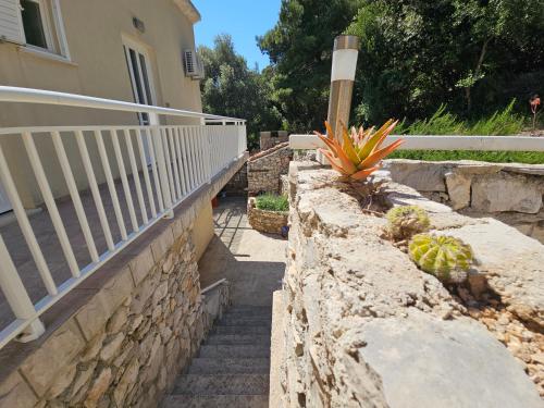 a stone retaining wall next to a house with stairs at Apartments Angela in Goveđari