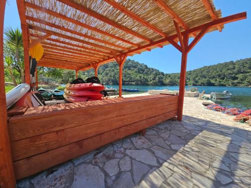 a wooden pergola with a boat on the water at Apartments Angela in Goveđari