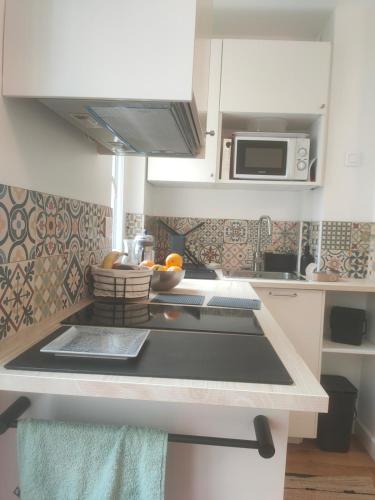 une cuisine avec un évier et un micro-ondes dans l'établissement Charmant studio au calme, à Paris