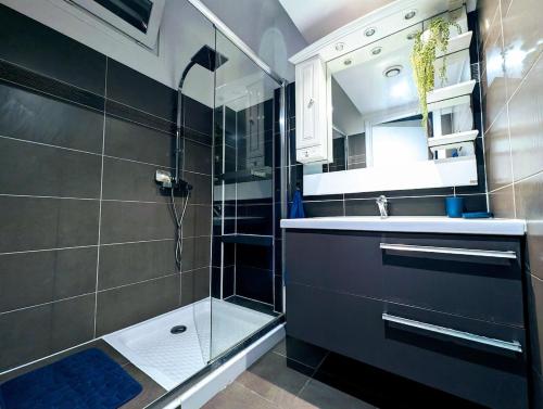 Un baño con ducha, lavabo y espejo. en Appartement familial - Vue mer, en Bastia