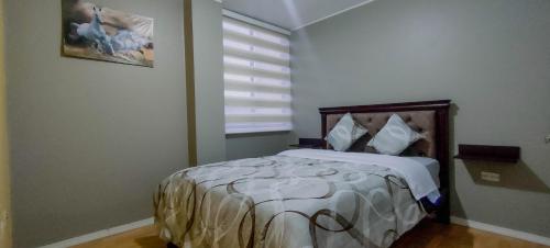a bedroom with a bed in a room with a window at Departamento en conjunto residencial in Riobamba