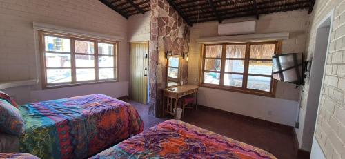 a room with two beds and a tv and windows at Sandy Shores Cabaña 8B in La Paz