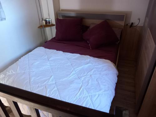 - un lit avec des draps blancs et des oreillers violets dans l'établissement Le CENTAURE Proche Centre Naturiste, au Cap d'Agde