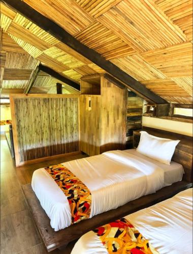 a bedroom with two beds and a wooden ceiling at La Roza Resort Masaka in Masaka