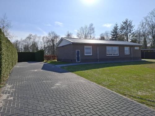 a house with a brick driveway in front of a yard at holiday home Nuil in Pesse