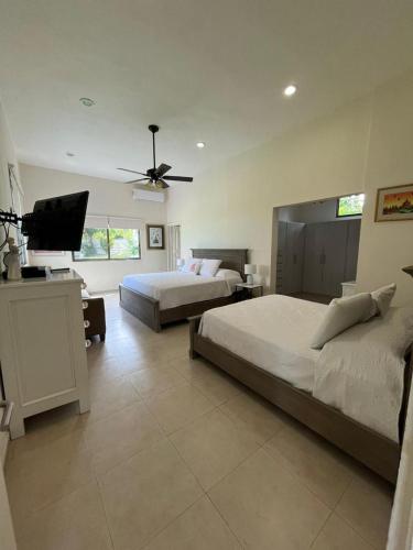 a bedroom with two beds and a flat screen tv at Villa Bianca Bacalar in Bacalar