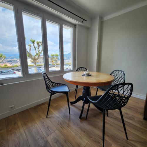 une table et des chaises dans une pièce avec des fenêtres dans l'établissement Charmant appartement au calme à proximité du Port, de la vieille ville de Nice , de la Promenade des Anglais, à Nice