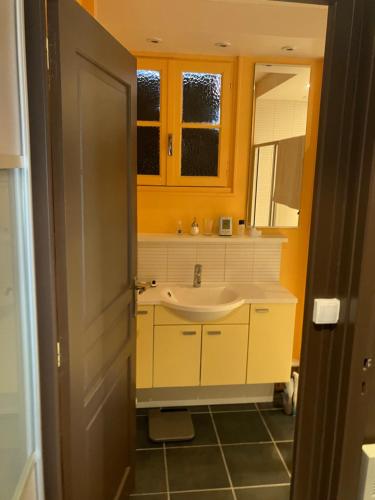 a yellow bathroom with a sink and a mirror at Chambres d hôte du Puy des Gardes in Meymac