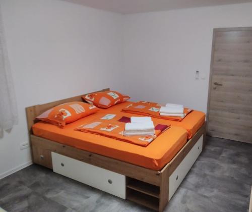 a bed with orange blankets and pillows on it at Apartment One2one in Bovec