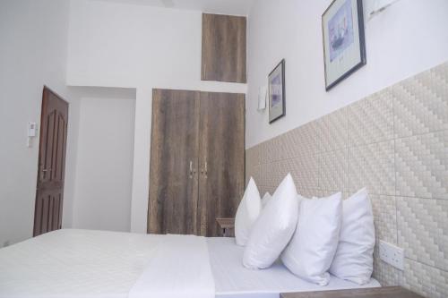 a bedroom with a white bed with white pillows at Urban Oasis Apartments in Mombasa