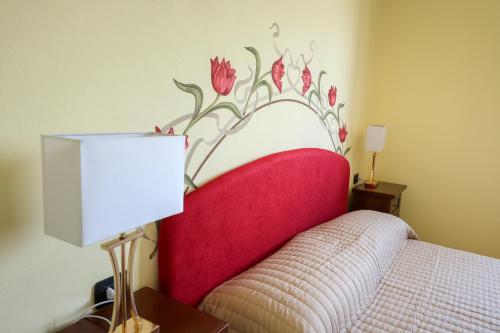 a bedroom with a red headboard with a flower mural on the wall at Agriturismo Agricola Cassiano in Morciano di Leuca