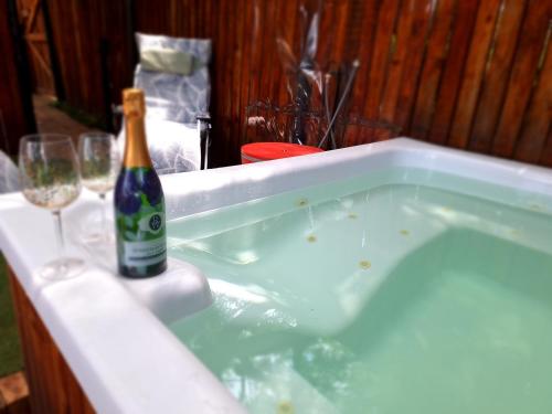 a hot tub with a bottle of champagne and glasses at Windsong Living The Nest in Krugersdorp