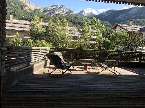 dos sillas en una terraza con montañas en el fondo en "Le CLOS DE L'YRET" Appartement avec grande terrasse en face des pistes, en Le Monêtier-les-Bains