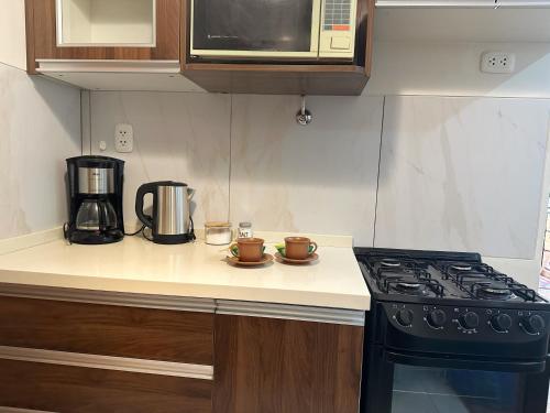 a kitchen counter with a stove and a microwave at Lujoso y soleado departamento en Sopocachi in La Paz