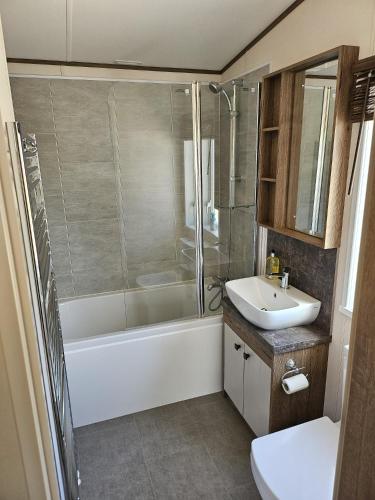 a bathroom with a shower tub and a sink at Still Waters Luxury Retreat with Hot Tub -Tattershall Lakes in Tattershall