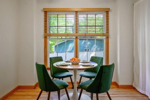 a table with green chairs in a room with a window at 4 Beds ,King Bed, Tvs, Kids essentials, office, Grill, Crib, in Bond park ,PNC Arena in Cary