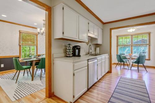 a kitchen with white cabinets and a dining room with a table at 4 Beds ,King Bed, Tvs, Kids essentials, office, Grill, Crib, in Bond park ,PNC Arena in Cary