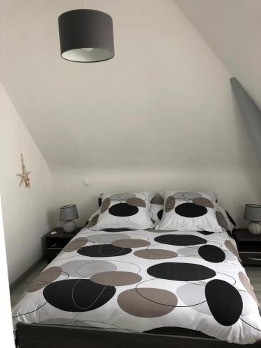 - un grand lit avec des draps et des oreillers en noir et blanc dans l'établissement Terrasses de la Mer Brehec, à Plouha