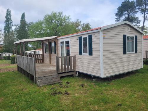 Une petite maison blanche assise sur une pelouse dans l'établissement mobil home, à Lit-et-Mixe