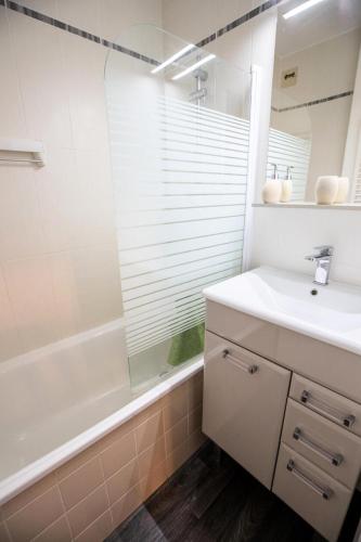 une salle de bain avec un lavabo, une baignoire et un miroir dans l'établissement Résidence Les Campanules - LES CAMPANULES - CA13FC MAE-3198, à Villarodin-Bourget