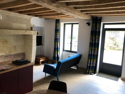 un salon avec une chaise bleue et une cheminée dans l'établissement Petite maison dans fosse troglodytes, à Chemellier