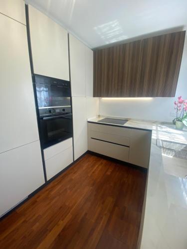 une cuisine avec des armoires blanches et un plancher en bois dans l'établissement T4 - proche Monaco a 250m de la plage - 3 lits doubles -6 personnes, à Roquebrune-Cap-Martin