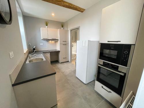 une cuisine avec des armoires blanches et un appareil noir dans l'établissement Gîte des Ouches 2, à La Chapelle-Vieille-Forêt