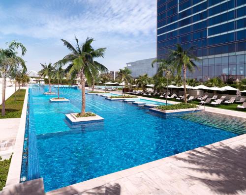 a large swimming pool with palm trees and a building at Fairmont Bab Al Bahr in Abu Dhabi
