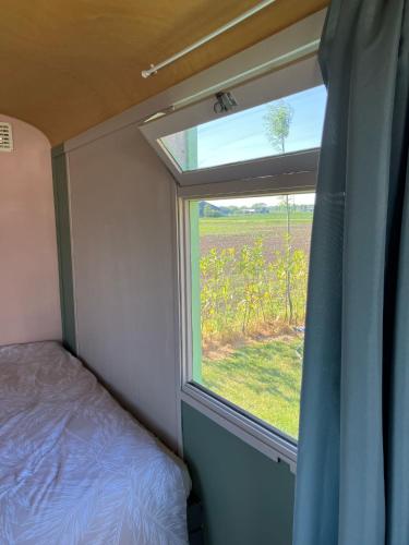 a bedroom with a window with a view of a field at De Keet op een boerencamping in Klundert