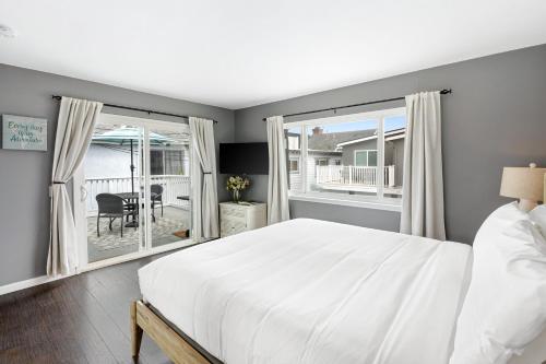 una camera da letto con un grande letto bianco e finestre di Topside Newport Rooftop Balcony Ocean Views Walk to Pier Marina Village a Newport Beach