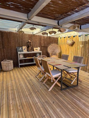 a patio with a table and chairs on a wooden floor at Ty Baradoz, Maison vue mer et plage à pied in Névez