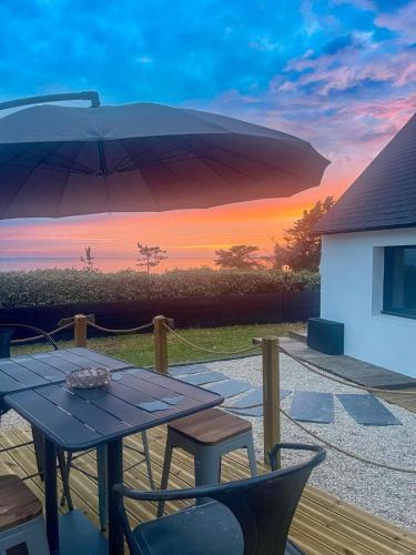 a table and chairs with an umbrella on a patio at Ty Baradoz, Maison vue mer et plage à pied in Névez